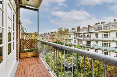 Eski tuğla binaların panoramik manzarası. Küçük balkondan park yerleri ve ağaçlar.