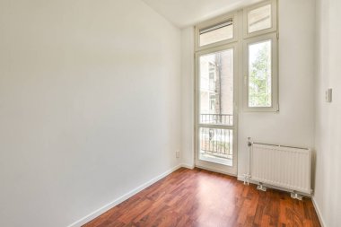 Evdeki boş ışık odasında, beyaz duvardaki plastik pencere ve radyatör.