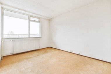 Evdeki boş ışık odasında, beyaz duvardaki plastik pencere ve radyatör.