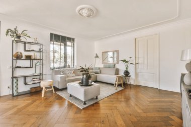 Çağdaş bir dairede pencerelere karşı şık mobilyaları olan geniş bir odanın içinde.