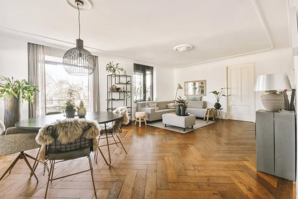 Interior of spacious room with stylish furniture against windows to balcony in contemporary apartment