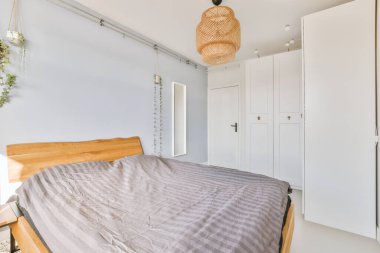 Chandalier 'in altındaki komodinin altında rahat bir yatak odası pencere ve balkon kapısının yanına konmuş bir lamba.