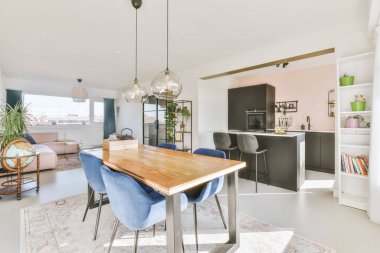 Pandantif lambanın altındaki ahşap yemek masası açık mutfak ve oturma odası.