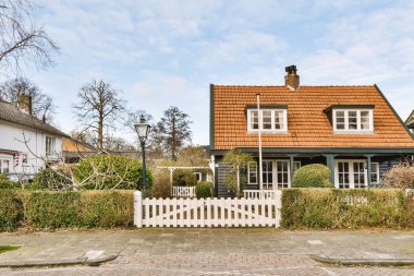 Arabaları, ağaçları ve fenerleri olan boş bir kaldırımdan panorama manzaralı evler.