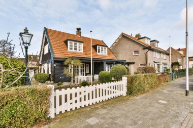 Arabaları, ağaçları ve fenerleri olan boş bir kaldırımdan panorama manzaralı evler.