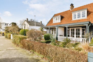 Arabaları, ağaçları ve fenerleri olan boş bir kaldırımdan panorama manzaralı evler.