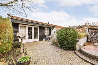 Oturma alanı ve ahşap çitlerin yanındaki küçük bahçesi olan düzgün asfaltlı bir avlu.