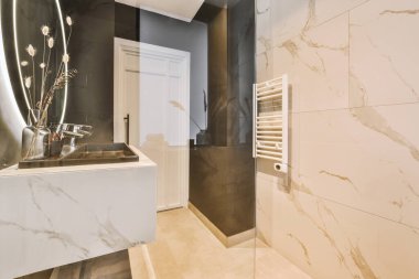 Lavabo ve aynalı dolap kapının yanındaki fayanslı duvara ve modern tuvaletteki kurutma tezgahına bağlı.