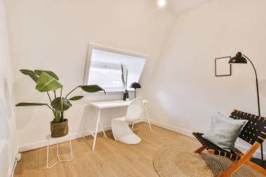 Mansard Light Home Office 'deki masanın yanına, güncel dairede rahat bir sandalye yerleştirildi.