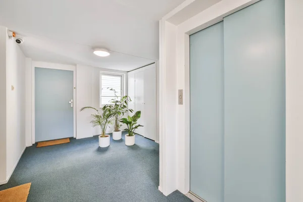 Corridor of contemporary apartment with blur doors and doorway leading to terrace