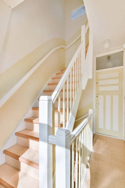 Staircase with white railings connecting the levels of a modern house with wooden floor and white walls