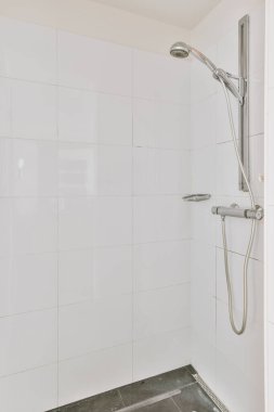 Aynalı lavabo ve temiz küvet modern banyoda cam kapılı ve beyaz fayanslı duvarları olan duş kutusunun yanında.