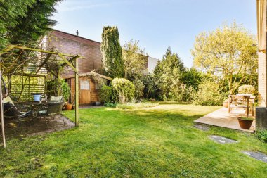 Oturma alanı ve ahşap çitlerin yanındaki küçük bahçesi olan düzgün asfaltlı bir avlu.