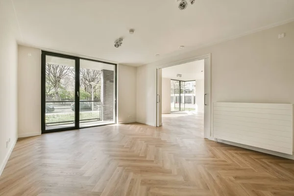 Spacious bright empty room with panoramic windows and parquet floor