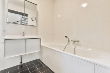 Aynalı lavabolar ve modern banyoda beyaz fayanslı duvarları olan temiz bir küvet.