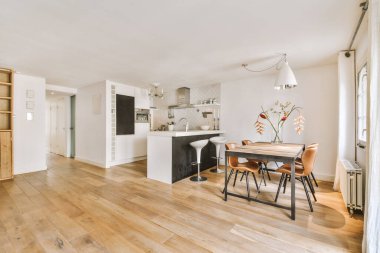 Beyaz duvarlı stüdyo daire, açık mutfak ve oturma odasında kanepesi olan yemek salonu.