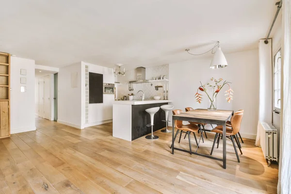 Beyaz duvarlı stüdyo daire, açık mutfak ve oturma odasında kanepesi olan yemek salonu.