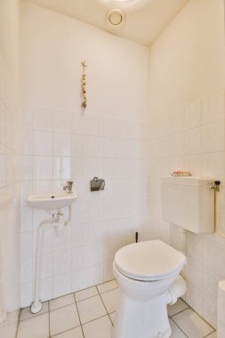 Modern sifon tuvalet ve seramik lavabo evdeki küçük tuvaletteki beyaz fayanslı duvarlara monte edildi.