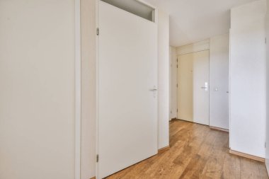 Minimalist tarzda bir dairede beyaz duvarları ve parke zemini olan boş dar koridor manzarası