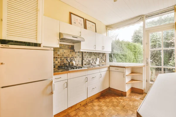 Contemporary counters and stools located under stylish exhaust hood in spacious light kitchen at home