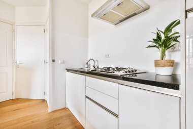 Minimalist tarzı beyaz mobilyalı, lavabolu ve sobalı bir ev mutfağı.