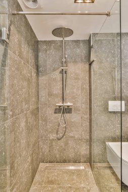 Duş muslukları cam bölmenin yanındaki fayanslı duvara bağlanmış ve evdeki banyoda duş kabini ve geniş kablosuz lavabo ile süs perdesi var.
