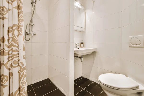 白いタイル張りの壁を持つモダンなバスルームでガラスドアとシャワーボックスの近くにミラーときれいなトイレとシンク — ストック写真