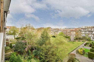 Eski tuğla binaların panoramik manzarası. Küçük balkondan park yerleri ve ağaçlar.