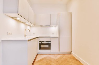 Arka farları ve ahşap parke zemini olan boş beyaz mutfağın içi.