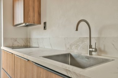 Beyaz duvarları ve fayanslı zemini olan geniş, parlak bir mutfak.