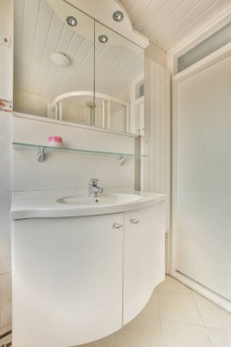 Lavabo ve aynalı dolap kapının yanındaki fayanslı duvara ve modern tuvaletteki kurutma tezgahına bağlı.