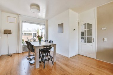 TV 'nin yanındaki koltuklar ve masa, çağdaş apartmandaki geniş odalı yemek alanına karşıdır.