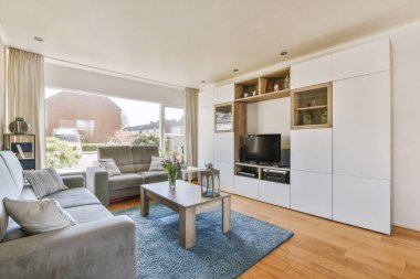 TV 'nin yanındaki koltuklar ve masa, çağdaş apartmandaki geniş odalı yemek alanına karşıdır.