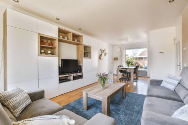 TV 'nin yanındaki koltuklar ve masa, çağdaş apartmandaki geniş odalı yemek alanına karşıdır.