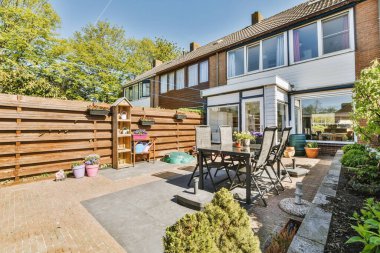 Oturma alanı ve ahşap çitlerin yanındaki küçük bahçesi olan düzgün asfaltlı bir avlu.