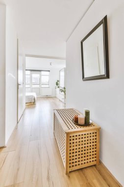 Beyaz duvarları ve kapıları olan dar koridor modern dairede pencereleri ve parke zemini olan geniş odaya açılıyor.