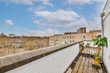 Evlerin panoramik manzarası, avlu ve mavi gökyüzü balkondan bulutlarla kaplı.