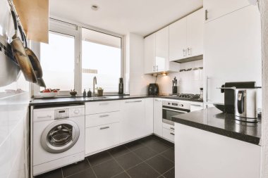 Beyaz mobilyalar ve aletlerle çatı katı tarzı bir dairede modern ev mutfağı iç tasarımı.