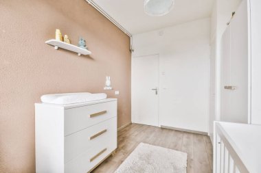 Küçük yatak odasının minimalist iç tasarımı. Köşesinde yumuşak yatak, ahşap gardırop ve lamba aydınlatmalı raflar var.