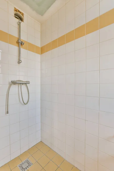 ガラスパーティションの近くのタイル張りの壁に取り付けられたシャワー蛇口と自宅の洗面所の装飾用カーテン — ストック写真