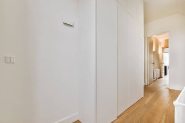 Dar, boş koridor lambalarla aydınlatılmış, minimal tarzda modern dairenin içi