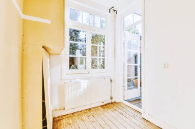 Evdeki boş ışık odasında, beyaz duvardaki plastik pencere ve radyatör.