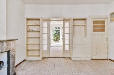 Tabureli modern tezgahlar, beyaz duvarlı, geniş odalı şöminenin yanındaki ahşap zemine yerleştirilmiş.