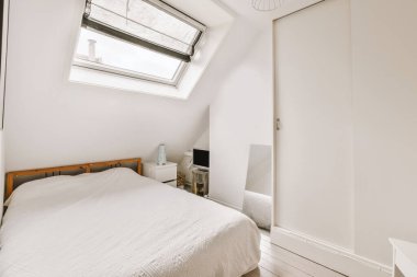 Modern minimalist tarzda pencereli mansard yatak odasındaki yeşil duvarın yanına konforlu yatak