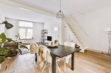 TV 'nin yanındaki koltuklar ve masa, çağdaş apartmandaki geniş odalı yemek alanına karşıdır.