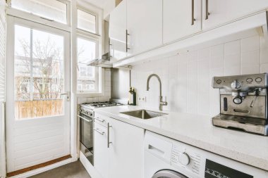 Minimalist tarzı beyaz mobilyalı, lavabolu ve sobalı bir ev mutfağı.