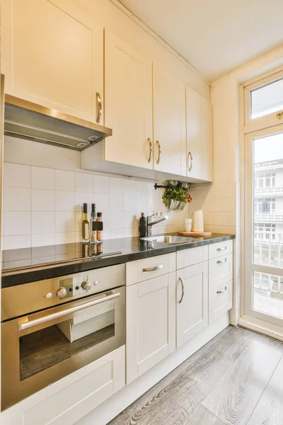 Interior of a bright kitchen with balcony doors in a modern apartment at daytime