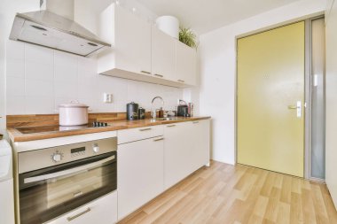 Çağdaş dairenin geniş odasındaki dinlenme odası ve mutfağın yakınındaki sandalyeli ve çiçekli masa.