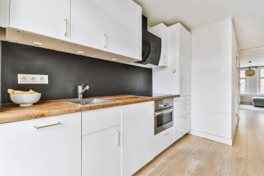 Minimalist tarzı beyaz mobilyalı, lavabolu ve sobalı bir ev mutfağı.