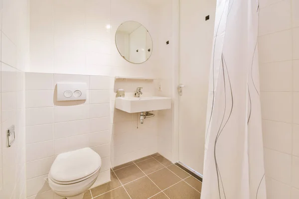 白いタイル張りの壁と光のシンクとトイレの近くにオープンシャワー付きのバスルーム — ストック写真